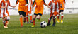 Cchildren having fun in soccer football game. Group of school kids running ball in football duel. School boys in sports outdoor competition. Children in red and orange soccer uniforms