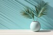  a white vase with a plant in it on a table with a shadow of a palm tree on the wall behind it.