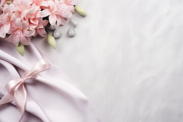  a bouquet of pink flowers sitting on top of a white satin table cloth with a pink ribbon on top of it.