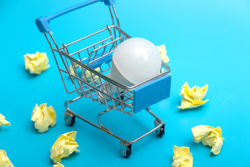 A white LED lamp in a supermarket cart against a background of crumpled notes. The concept of buying an idea. The franchisee.