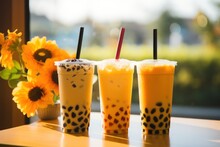  Three Drinks Sitting On Top Of A Table Next To A Vase Of Sunflowers And A Vase Of Sunflowers.