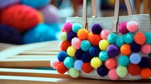A Close-up Of A Woven Straw Bag With Colorful Pom-pom Accents, Evoking A Sense Of Summer Fun.