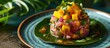 Tropical gourmet tuna mango salad tartar with cilantro and purple onion, served on blue plate with tropical leaves.