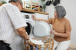 senior woman and her husband doing laundry together with washing machine at home