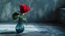 A Smooth, Matte Surface Holds A Slender Vase With A Single, Blooming Red Rose. 
