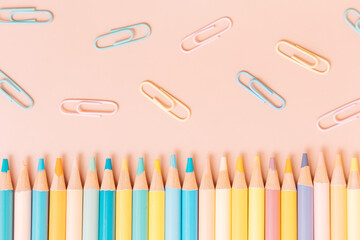 Colored pencils and paper clips on a beige background.