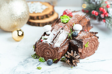 Wall Mural - Traditional  French Christmas chocolate dessert  BûchedeNoël (Yule log). Christmas festive pastry in the shape of a log on the white background with blurred bokeh lights