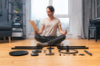 A perfectionist man carefully reads the instruction for assembling furniture, sitting on the floor in the lotus position, among neatly arranged parts and tools. Self-assembly of furniture from scratch