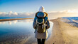 © HappymanPhotography - A girl with a backpack standing on the beach by the sea, looking out to sea. Travel concept