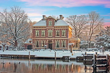 Canvas Print - Typical snowy dutch 15th century house in the countryside from the Netherlands in winter at sunset