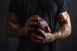 American Football player player holding american football on black blackboard texture background with copy space for text or design.
