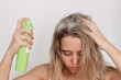 © Марина Демешко - Young blonde woman with dirty greasy hair spraying dry shampoo on the roots of her hair on a light background. The problem of oily scalp. A fast way to cleanse