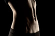 © vladimirfloyd - Close-up of a fit woman's stomach under the glow of light in a dark background