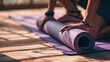 Close-up of a person's hands rolling up a purple yoga mat