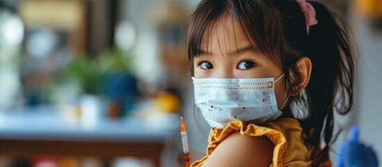 Child immunization concept: Asian girl displays arm post-COVID Delta vaccination.