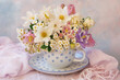 A bouquet of spring flowers in a cup on the table, a beautiful still life, a postcard