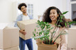© MyJuly - African American couple, man woman, collect clothes and plants in cardboard boxes for moving. happy young people relocating to new home. mortgage or rental of real estate. moving movers service