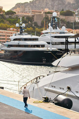 Wall Mural - Few huge luxury yachts at the famous motorboat exhibition in the principality of Monaco, Monte Carlo, the most expensive boats for the richest people, mountain and residential complex on background