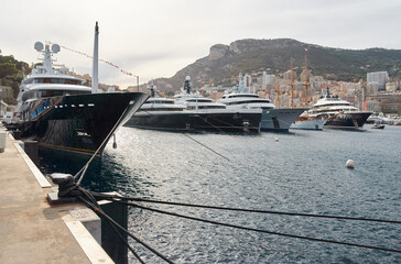 Wall Mural - Few huge luxury yachts at the famous motorboat exhibition in the principality of Monaco, Monte Carlo, the most expensive boats for the richest people, mountain and residential complex on background