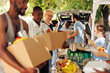 © DC Studio - Group of individuals smiling while distributing meal boxes and canned goods to needy. Young volunteers happily provide humanitarian aid to homeless people seniors and individuals seeking shelter.