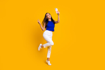 Poster - Full length photo of friendly cute woman wear blue top showing v-sing recording video gadget empty space isolated yellow color background