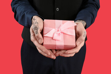 Man with gift for Valentine's day on red background