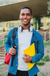 © Jose Calsina - Vertical individual portrait of a african american student young man carrying a backpack and note books at university campus. Teenage male smiling and looking at camera. High school guy staring front