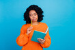 © deagreez - Photo portrait of lovely young lady writing essay notebook difficult wear trendy knitwear orange garment isolated on blue color background