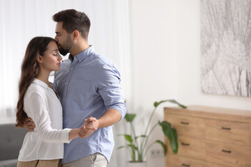 Wall Mural - Cute couple. Man kissing his girlfriend at home, space for text