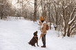 © New Africa - Woman with adorable Labrador Retriever dog in snowy park, space for text