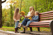 © New Africa - Happy mother and her children spending time together with dry leaves in autumn park