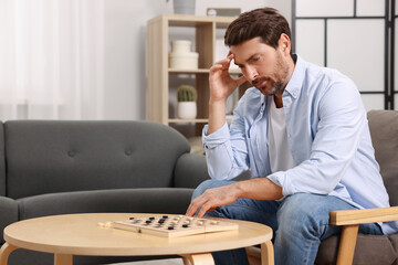 Canvas Print - Thoughtful man playing checkers at home. Space for text