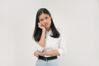 © Illhamt - A young Asian woman in a white shirt rests her chin on her hand, gazing thoughtfully with a neutral expression in a bright indoor setting during the day