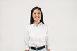 © Illhamt - Smiling brightly, a young Asian woman in a white shirt clasps her hands together indoors, radiating positive energy and enthusiasm in a workplace setting