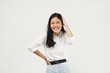© Illhamt - An Asian woman in a white blouse smiles warmly with her hand on her head. Set against a plain white background, she communicates confidence and positivity in her workplace.