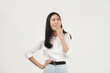 © Illhamt - An Asian woman in a white blouse covers her mouth while appearing thoughtful against a plain white background. She exudes a contemplative and professional vibe.