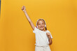 Young woman celebrating success on yellow background