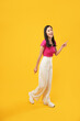 © Illhamt - Full body of length, vivid young woman Asian-looking camera moves isolated on a plain yellow background in a studio portrait. People's emotions lifestyle concept