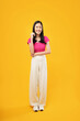 © Illhamt - An Asian woman stands confidently with her hand on her hip, radiating poise and positivity against a bold yellow background