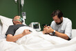 An elderly man is lying in a hospital bed, visited by his son. His son's presence brings comfort and joy, lifting his spirits during this time of recovery.
