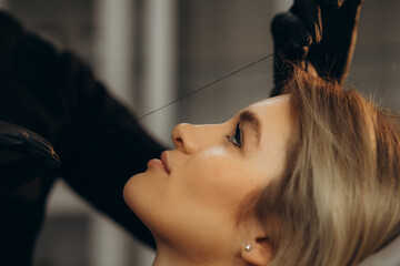 Wall Mural - Grooming the eyebrows thread in a beauty salon. close