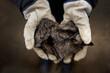 Two gloved hands holding a piece of ore from an Oil Sands site