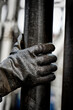 Human hand wearing a pair of gloves on oily drilling pipe