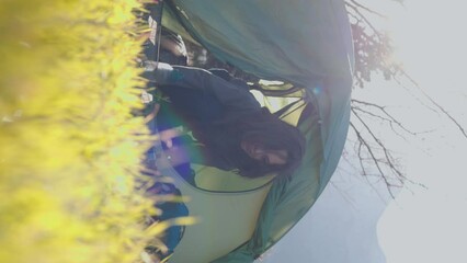 Sticker - vertical shot. the boy comes out of the tent and looks at the mountains. the child sleeps in a tent. morning in the mountains.