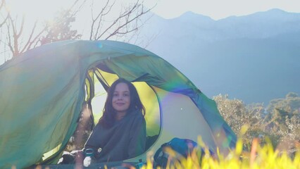 Sticker - A child sits in a tent and looks at the mountains. boy resting in a tent. Hiking in the mountains with a child. active lifestyle.