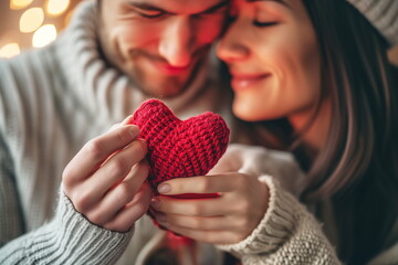 Cute couple holding together red fabric heart on Valentine's Day