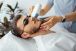 © Dasha Petrenko - Young man receiving photo epilation while visiting beauty center on salon