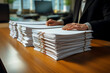 The hands of a male office worker in a business suit are sorting through documents stacked in a high pile