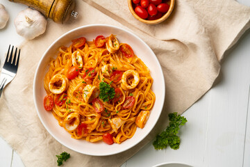 Wall Mural - Linguine pasta with squid and cherry tomato in tomato sauce in white plate.Top view