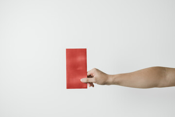 A hand holds angpao or red monetary gift on white background. Chinese New Year concept. Gong Xi Fa Cai.